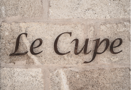Insegna in ferro Le Cupe installata su muro in pietra