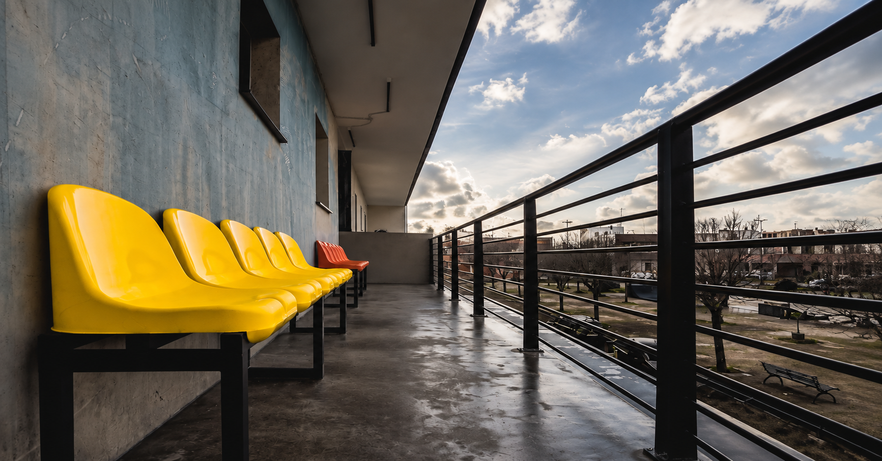 Ringhiera in ferro nera su terrazza con sedie gialle