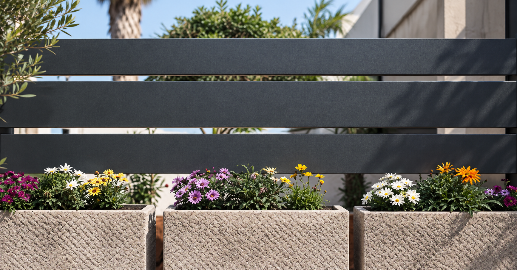 Recinzione in ferro grigio antracite con fioriere in pietra e fiori colorati